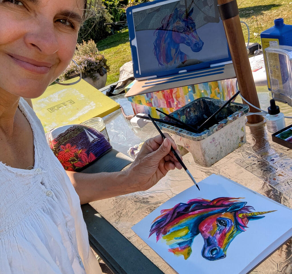 Heather with a finished painting of a unicorn